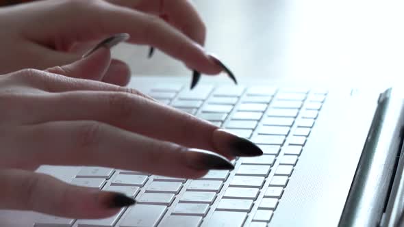 Female Hands of a Woman Typing on a Laptop Keyboard While Sitting at Her Desk