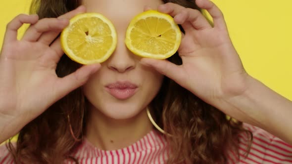 Young Woman Kissing Lips with Lemon Slices in Front of Eyes