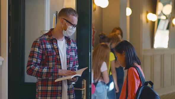 Young Teacher Standing at School Entrance Not Letting Students in Without Safety Mask