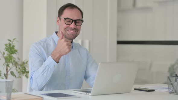 Middle Aged Man with Laptop Showing Thumbs Up