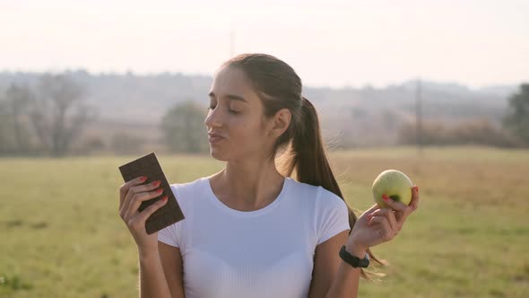 Girl Trying To Choose Between Chocolate And Apple