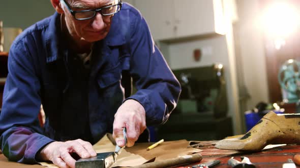 Shoemaker cutting a piece of leather