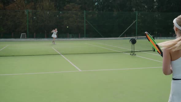 Back View of Female Tennis Player Hits the Ball with a Racket Female Hits Off the Opponent's Serves