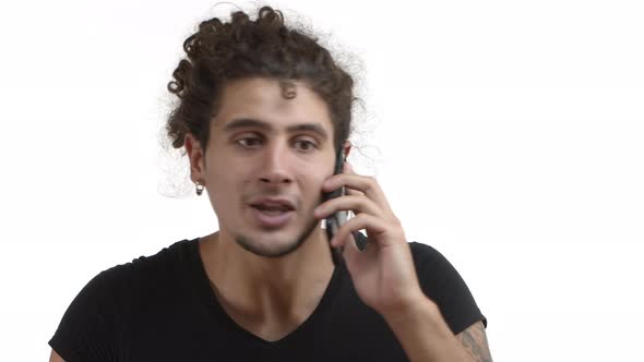 Closeup of Young Handsome Hispanic Man with Combed Curly Haircut and Beard Talking on Mobile Phone