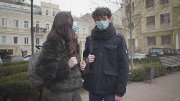 Portrait of Young Caucasian Male College Student in Face Mask Talking To Female Groupmate Outdoors