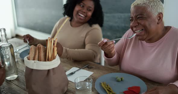 Happy black family eating lunch at home - Father, daughter, son and mother having fun together