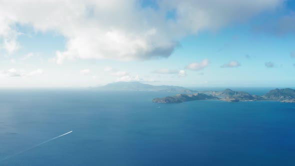 Drone camera shot of two yachts heading towards a hilly island in Saint Kitts and Nevis