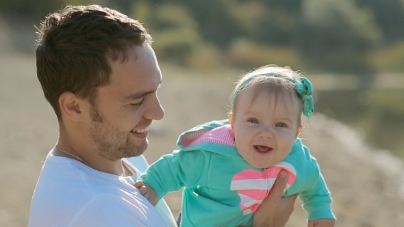 Dad Holding On Hands His Baby Daughter Near The