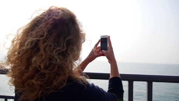 Woman Taking Pictures Of Sea With Smartphone