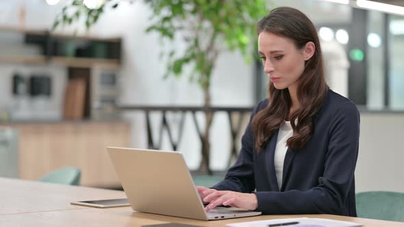 Businesswoman with Headache Using Laptop at Work 