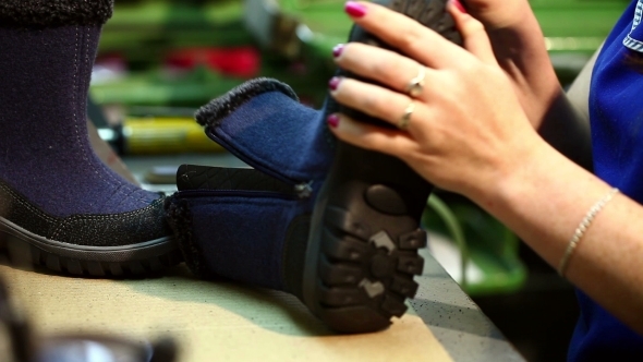 Manufacture Of Footwear. Worker Aligns Boot's Sole