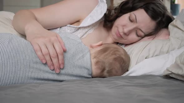 Mother in Breastfeeding Newborn Relaxing on Bed