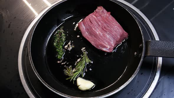 Large Steak Is Fried in a Frying Pan in the Kitchen of the Restaurant in Close-up