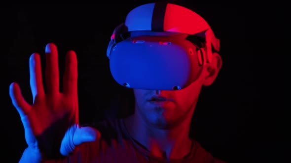 Young Man in VR Helmet Interacts with Virtual Reality and Media Content