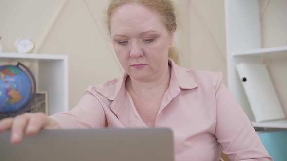 Senior Redhead Woman Closing Laptop and Looking at Camera. Lady Expressing Opposite Emotions