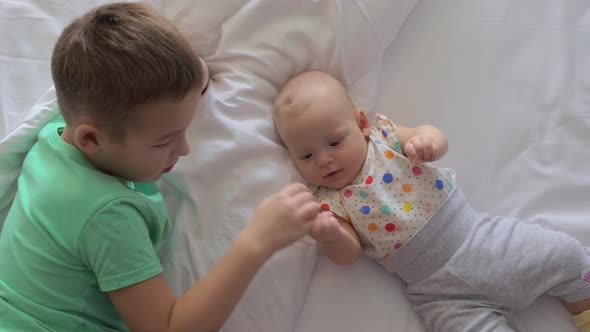 Boy and Baby Girl Siblings on Bed at Home