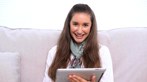Smiling Brunette Using Tablet Pc On Sofa alt