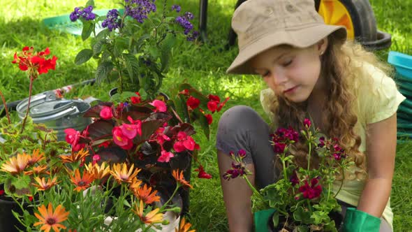 Cute Girl Holding A Pot Of Flowers In The Garden