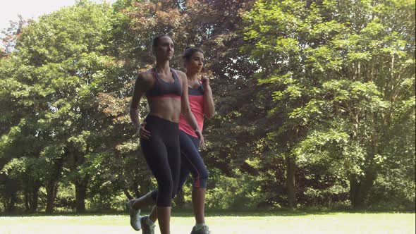 Two Friends Jogging Together In The Park On Sunny Day