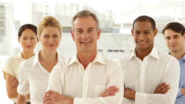 Businessman Smiling At Camera With Staff Behind Him alt