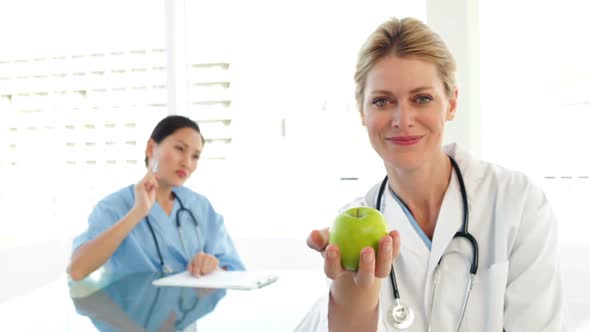 Smiling Doctor Showing A Green Apple alt
