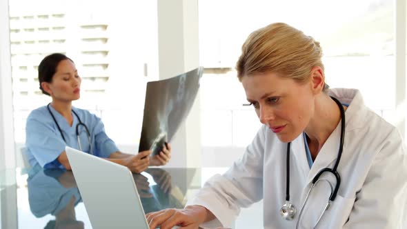 Smiling Doctor Using A Laptop Sitting At Table alt