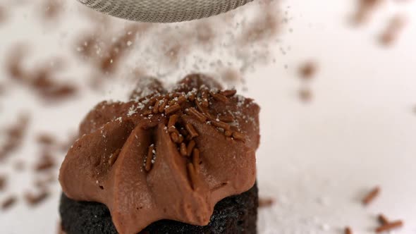 Icing Sugar Being Sieved On Chocolate Cupcake
