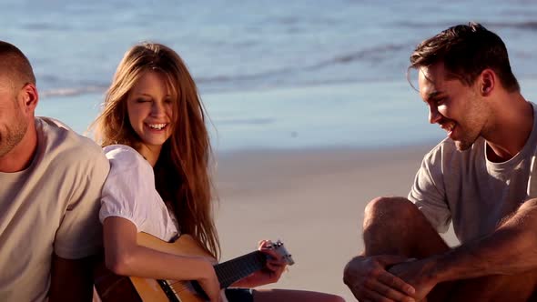 Smiling Friends Sitting On The Beach