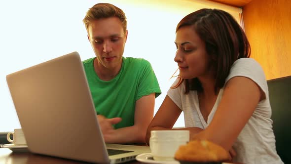 Friends Chatting In The Canteen Over Coffee Using Laptop