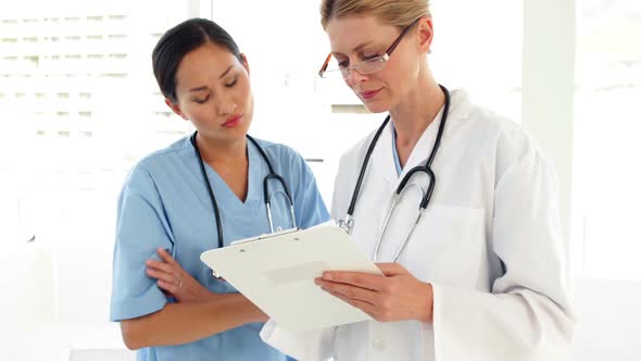 Two Medical Workers Looking Over A File And Looking At Camera