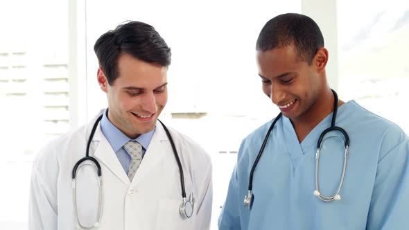 Two Medical Workers Looking Over File On Clipboard