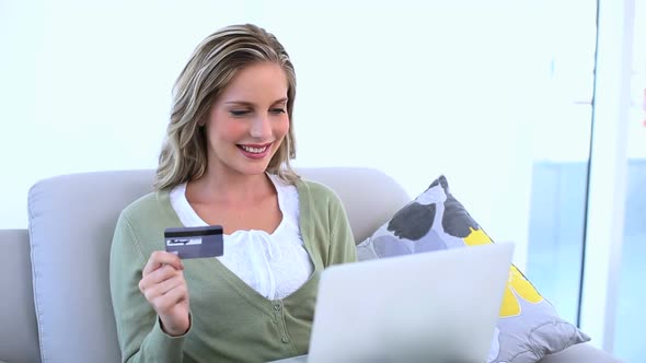 Delighted Woman Holding Her Credit Card And Using Her Laptop