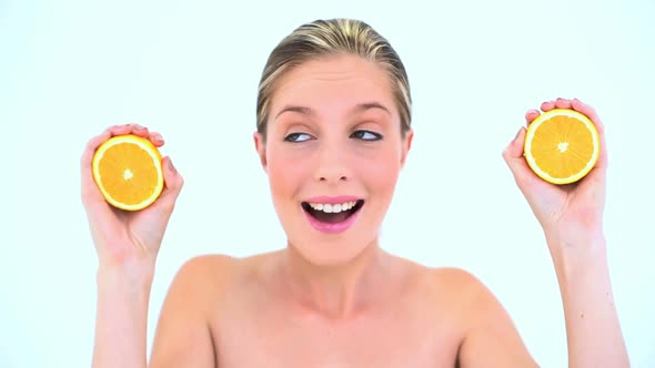 Blond Woman Holding Two Slices Of Orange alt