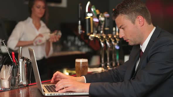 Businessman Working On His Laptop While Having A Beer