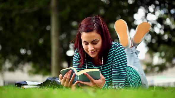 Pretty Student Lying On Grass Reading A Book Listening To Music