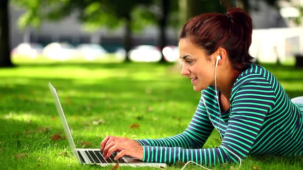 Pretty Student Lying On Grass Using Laptop Listening To Music alt