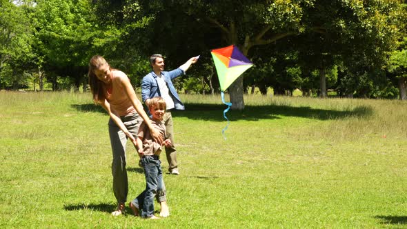 Little Boy And Parents Flying A Kite And Messing In The Park