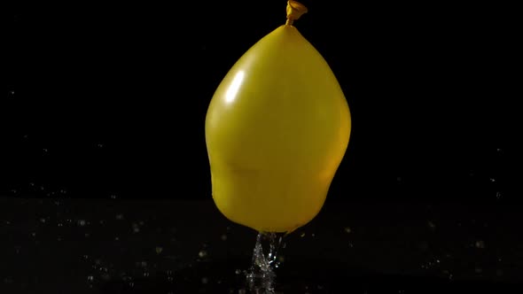 Yellow Water Balloon Falling On Black Background