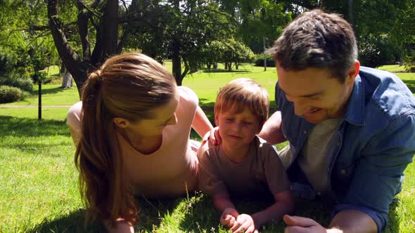 Little Boy And Parents Smiling At Camera In The Park