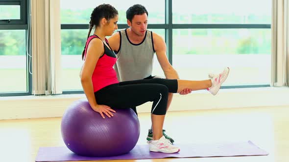 Pretty Woman Training Sitting On Fitness Ball With Coach