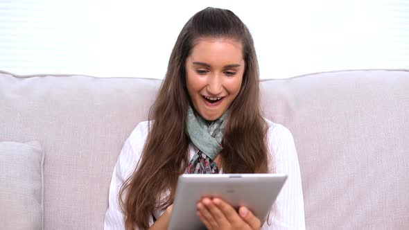 Cheerful Brunette Using Tablet Pc On Sofa alt