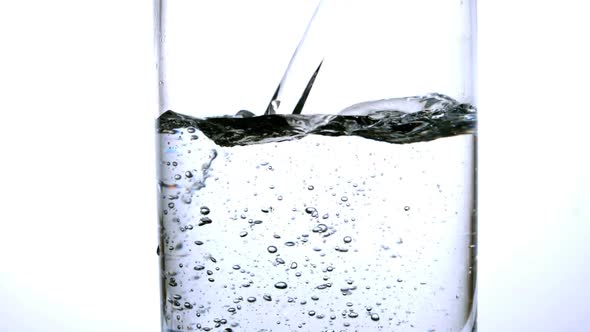 Water Being Poured Into A Glass Over White Background