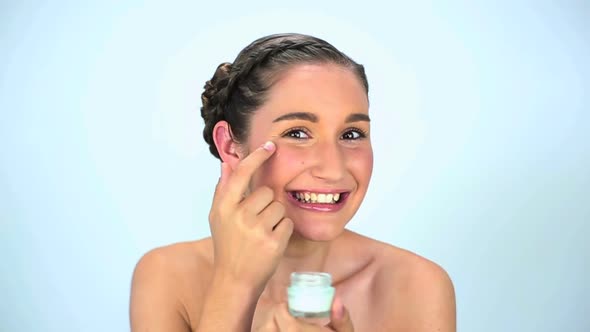Young Woman Applying Cream On Her Face