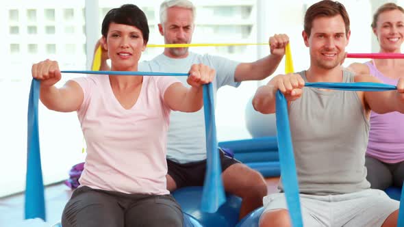 Group Sitting On Exercise Balls Stretching Resistance Bands alt