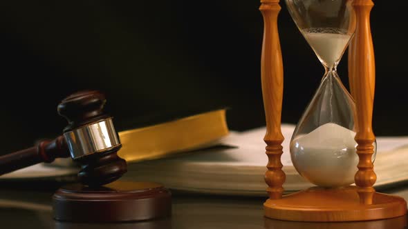 Sand Flowing Through Hourglass Beside Gavel And Bible alt