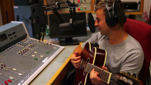 Student Singing And Playing Guitar In The Recording Studio