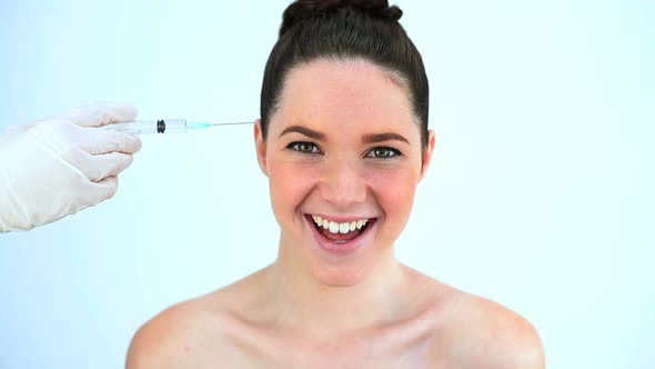 Hand Putting A Syringe On The Forehead Of A Beautiful Woman