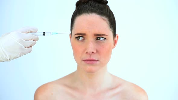 Hand Putting A Syringe On The Forehead Of A Troubled Woman