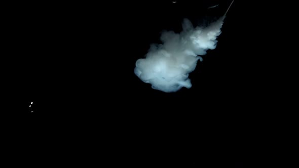 White Paint Dropping In Water On Black Background alt