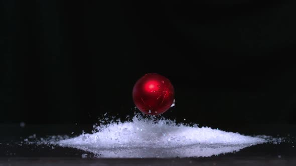 Christmas Bauble Falling Onto Pile Of Glitter On White Background